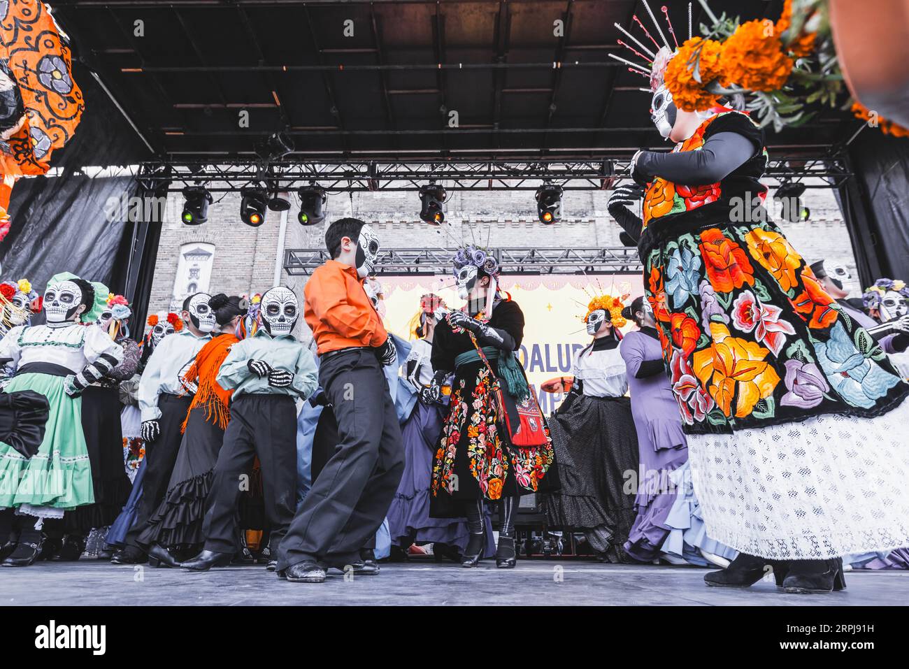Des gens dansant sur scène au festival Dias de Los Muertos, vêtus de costumes spécifiques et portant des masques de crâne de sucre Banque D'Images
