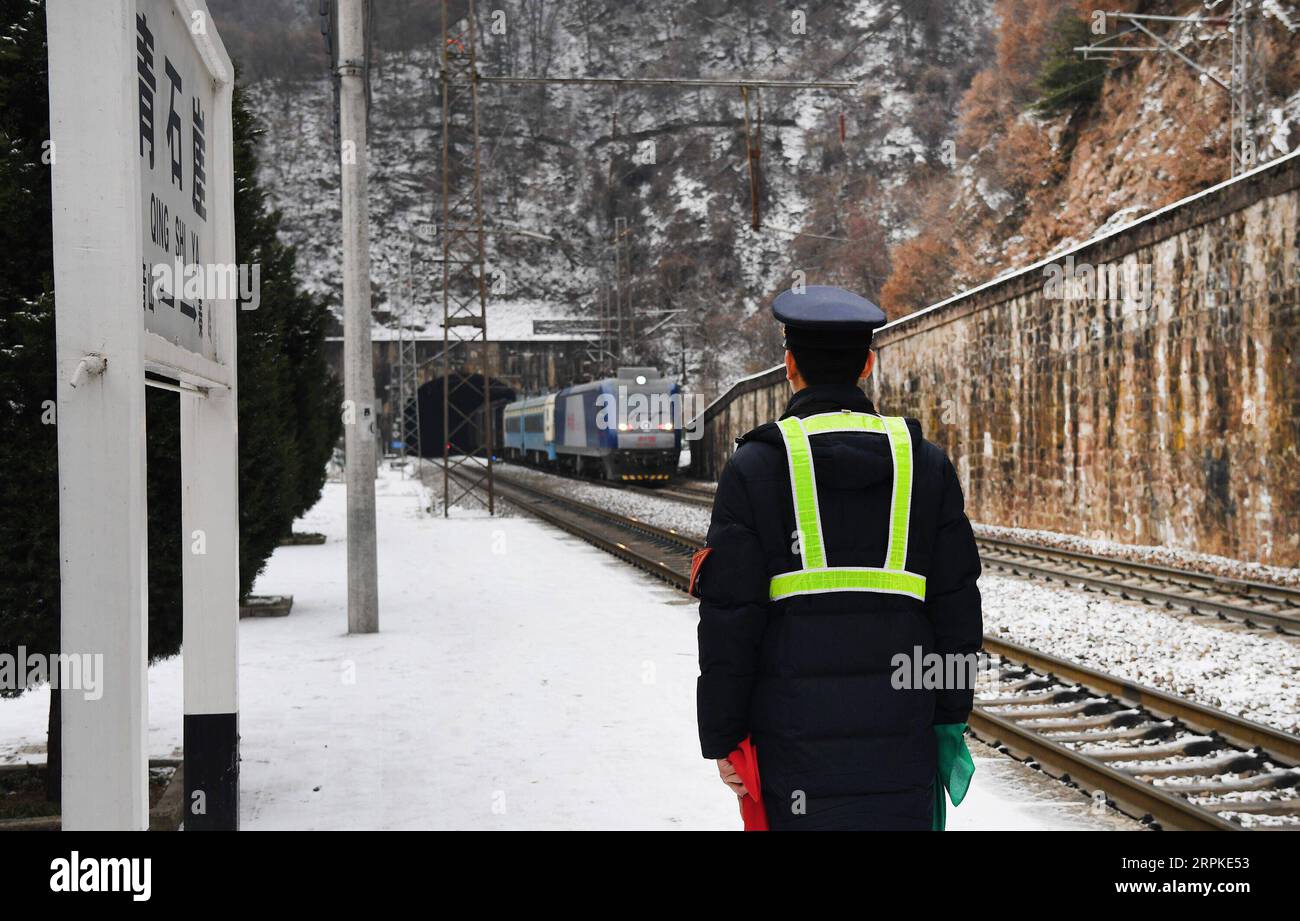 200109 -- BAOJI, le 9 janvier 2020 -- l'officier adjoint en service Zhao Shuai accueille le train à la gare de Qingshiya dans la ville de Baoji, dans la province du Shaanxi, au nord-ouest de la Chine, le 7 janvier 2020. La gare de Qingshiya est au sommet des montagnes de Qinling sur le premier chemin de fer électrifié de Chine, Baoji - Chengdu Railway. Entourée de falaises abruptes, la station des nuages se compose de seulement deux voies et sert de court arrêt pour les trains qui passent sur le chemin de fer. Aussi petite qu'elle soit, la station possède tous les organes vitaux. Pour garantir le fonctionnement de la gare, les membres du personnel de la gare travaillent sur la couverture 24/7/7. Banque D'Images