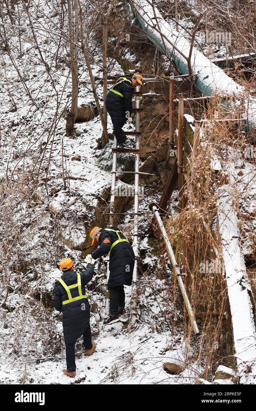 200109 -- BAOJI, 9 janvier 2020 -- des membres du personnel de la gare de Qingshiya montent des échelles pour draguer des conduites d'eau au sommet des montagnes de Qinling dans la ville de Baoji, dans la province du Shaanxi au nord-ouest de la Chine, le 7 janvier 2020. La gare de Qingshiya est au sommet des montagnes de Qinling sur le premier chemin de fer électrifié de Chine, Baoji - Chengdu Railway. Entourée de falaises abruptes, la station des nuages se compose de seulement deux voies et sert de court arrêt pour les trains qui passent sur le chemin de fer. Aussi petite qu'elle soit, la station possède tous les organes vitaux. Pour garantir le fonctionnement de la gare, les membres du personnel de la gare sont WO Banque D'Images