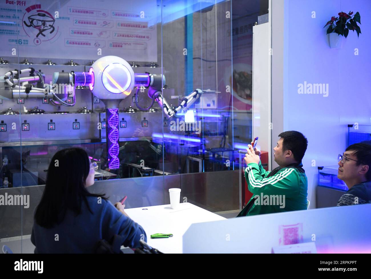 200116 -- GUANGZHOU, 16 janvier 2020 -- les clients regardent le robot de riz en pot d'argile travailler dans un restaurant intelligent à Guangzhou, capitale de la province du Guangdong du sud de la Chine, le 15 janvier 2020. Un restaurant chinois avec des robots de service intelligents a fait ses débuts dans le centre-ville de Guangzhou vendredi dernier, présentant des dizaines de spécialités sélectionnées parmi des centaines de plats préparés par les chefs robots. Au moment où les clients entrent dans le restaurant, leurs attentions sont prises par toutes sortes de robots intelligents qui ont des travaux spécifiques à faire : le robot de salutation debout à l’entrée pour guider les clients vers leur dinne Banque D'Images