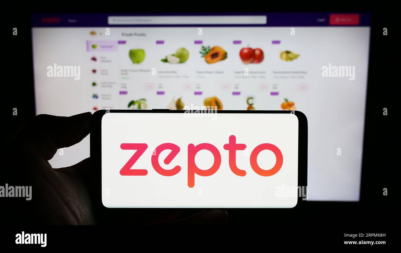 Personne tenant le téléphone portable avec le logo de la société indienne de livraison d'épicerie zepto sur l'écran en face de la page Web d'affaires. Concentrez-vous sur l'affichage du téléphone. Banque D'Images