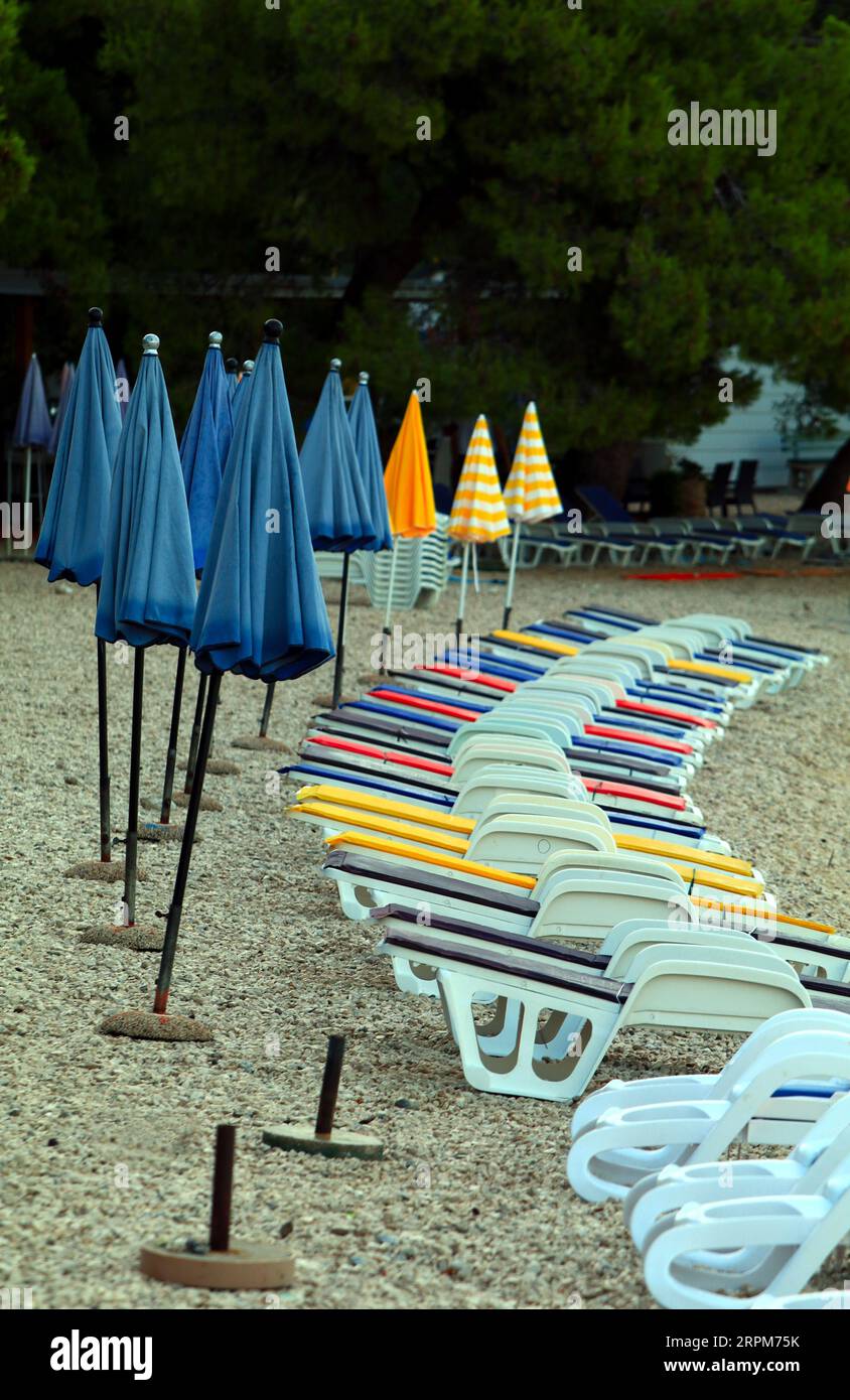 parasols colorés pliés sur la plage à côté des chaises longues Banque D'Images