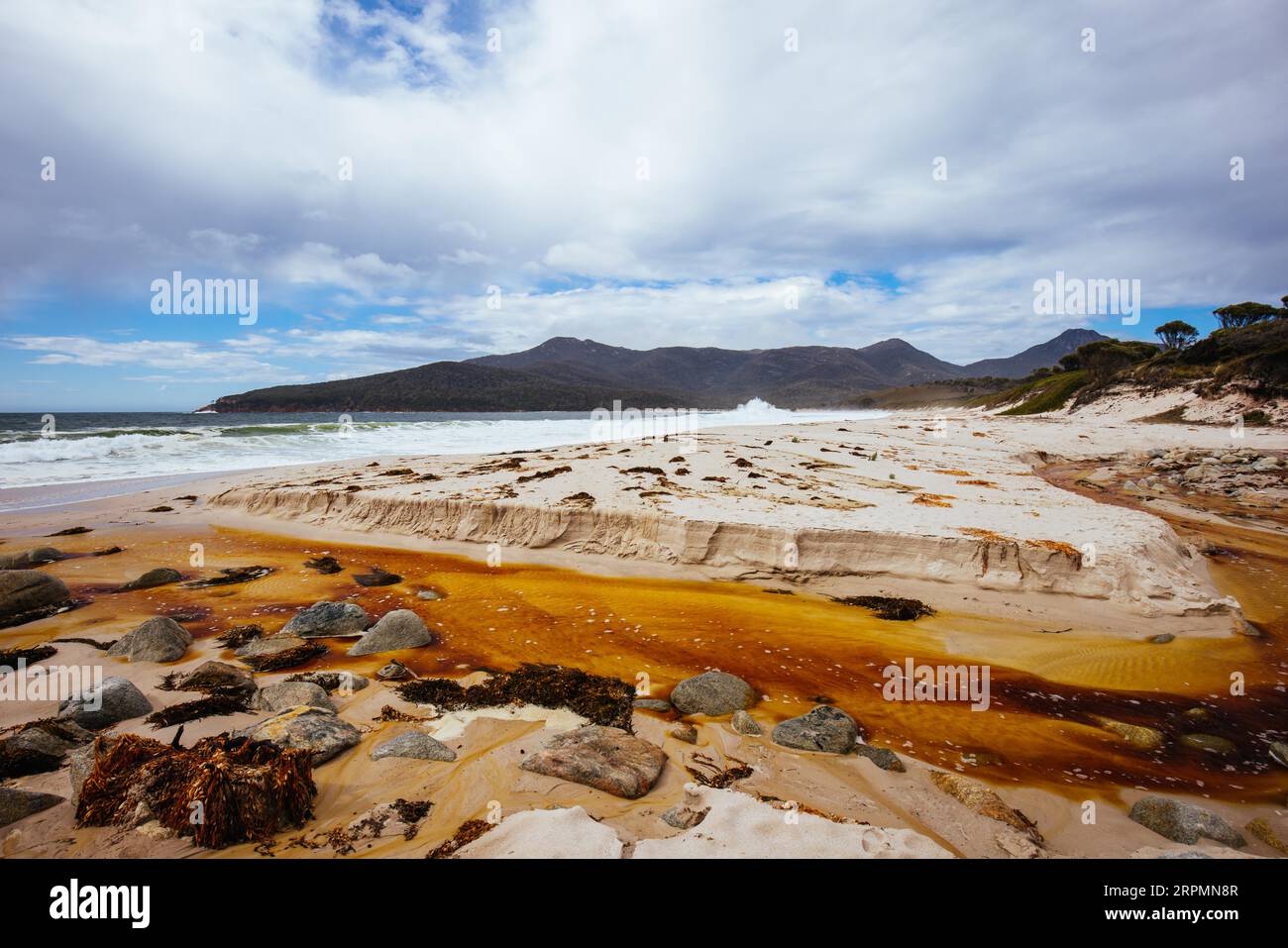 Wineglass Bay Beach et ses rochers de lichen oranges lors d'une journée difficile dans la péninsule de Freycinet en Tasmanie, en Australie Banque D'Images