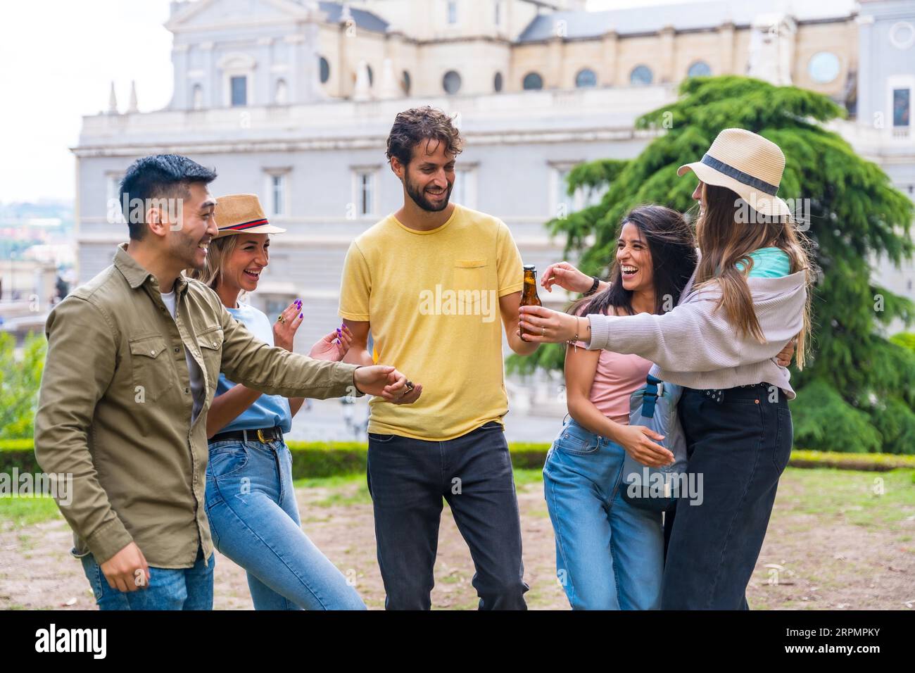 Groupe multi-ethnique d'amis faisant la fête dans un parc de la ville avec des bières. amusement d'été, salutations au nouvel ami qui est arrivé Banque D'Images