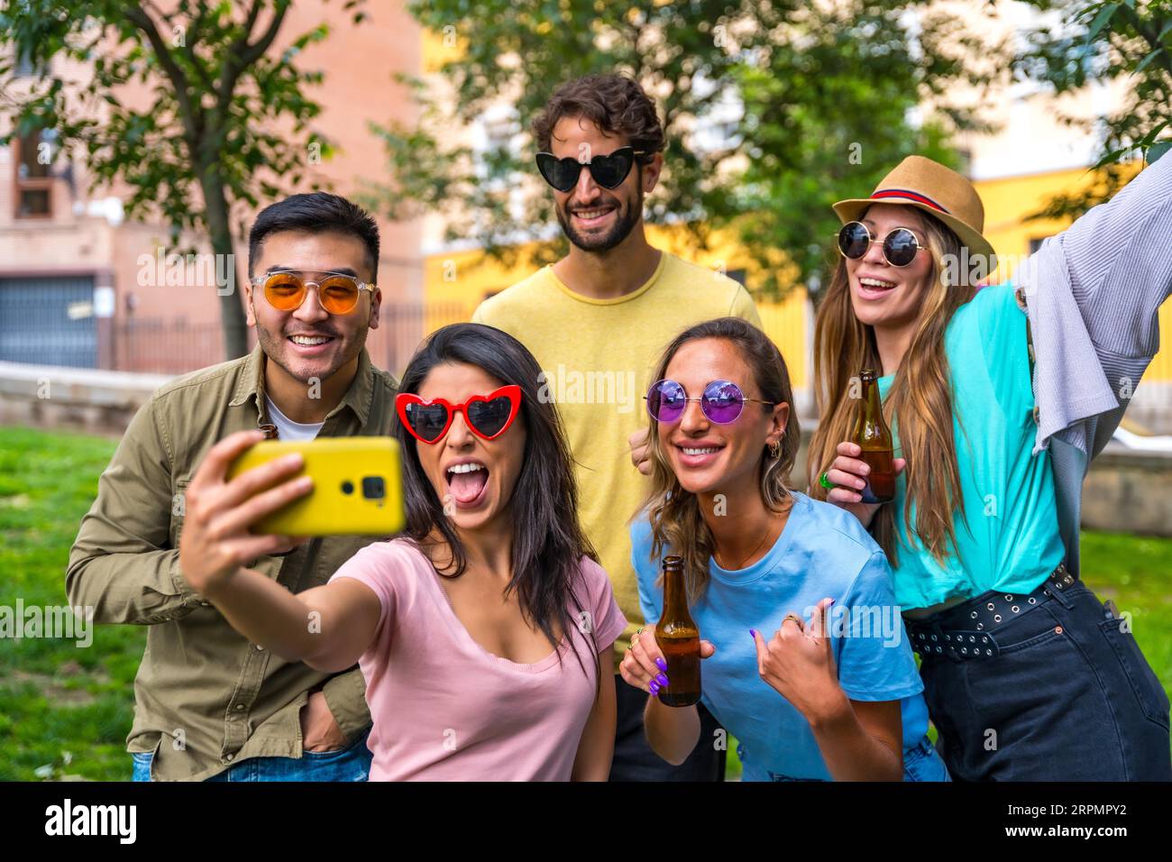 Groupe multi ethnique d'amis faisant la fête dans le parc de la ville en prenant un selfie, l'amitié et le concept amusant avec des lunettes de soleil Banque D'Images