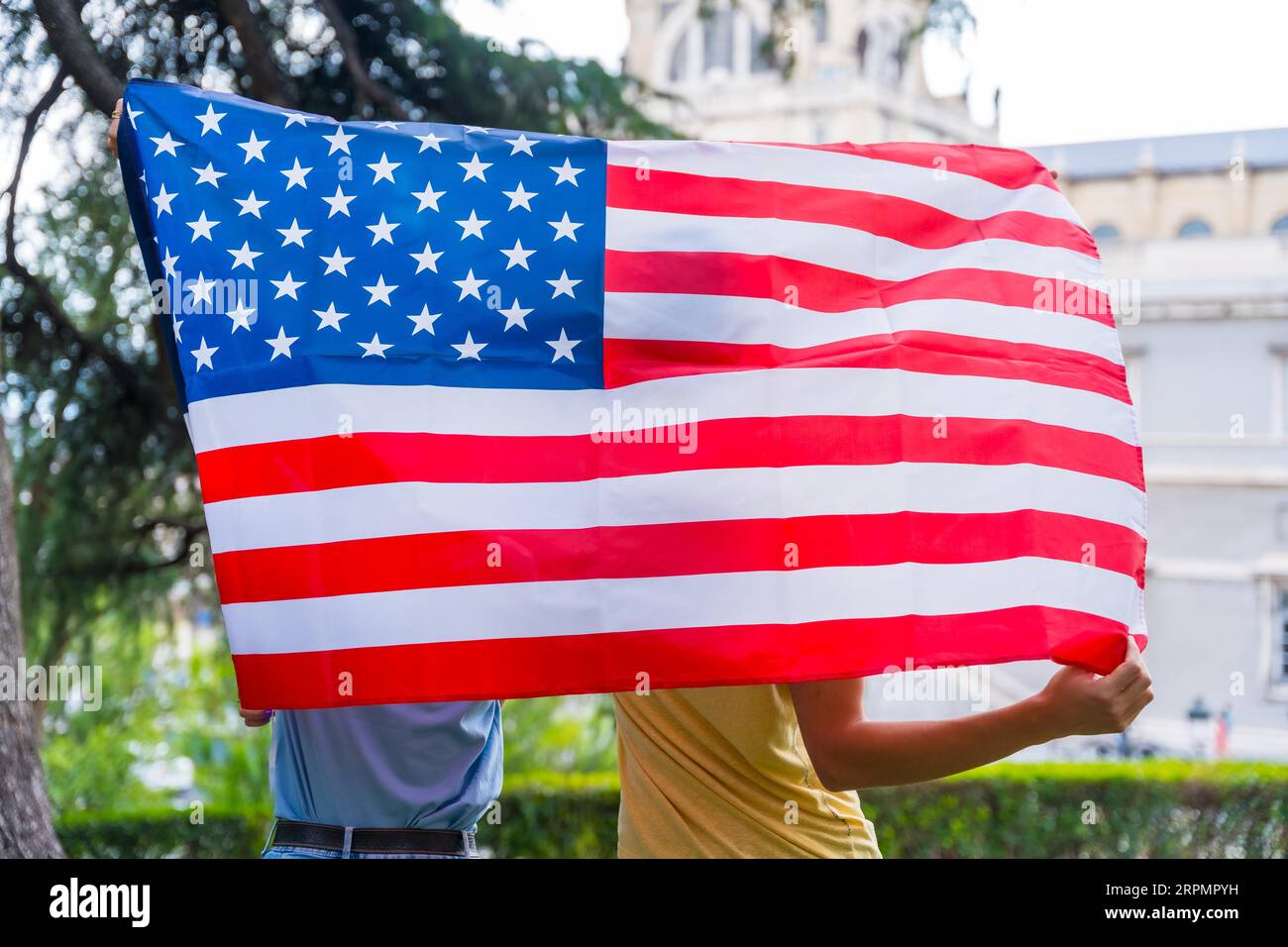 Couple dans la ville avec drapeau des états-unis, garçon et fille sur leur dos. Patriotes fiers de leur nation, jour de l'indépendance Banque D'Images