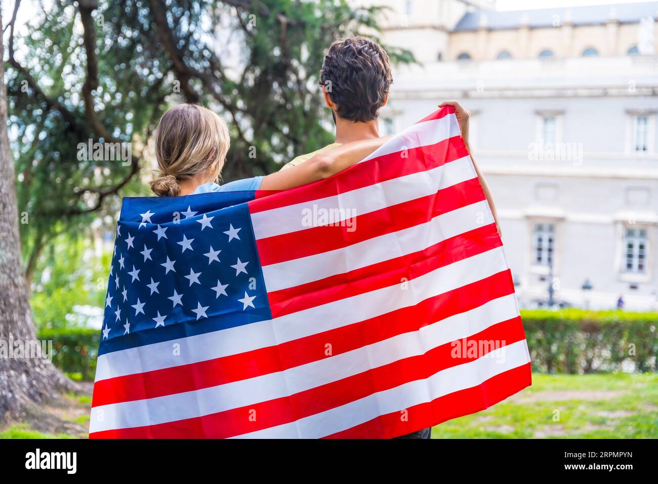 Couple dans la ville avec drapeau des états-unis, garçon et fille sur leur dos. Patriotes fiers de leur nation, jour de l'indépendance Banque D'Images