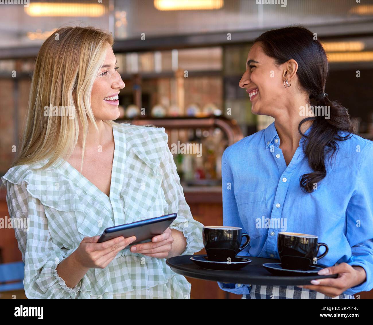 Femme Manager avec tablette numérique et serveuse travaillant dans un restaurant ou un café Banque D'Images