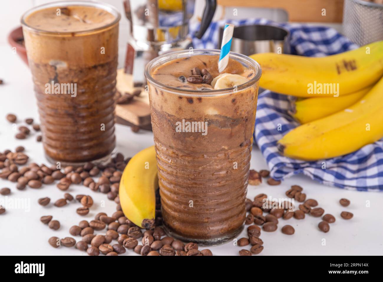 Café à la banane mélangé. Café au latte froid et banane non laitière, boisson diététique végétalienne avec bananes congelées et expresso, sur l'espace de copie de table de cuisine blanche Banque D'Images