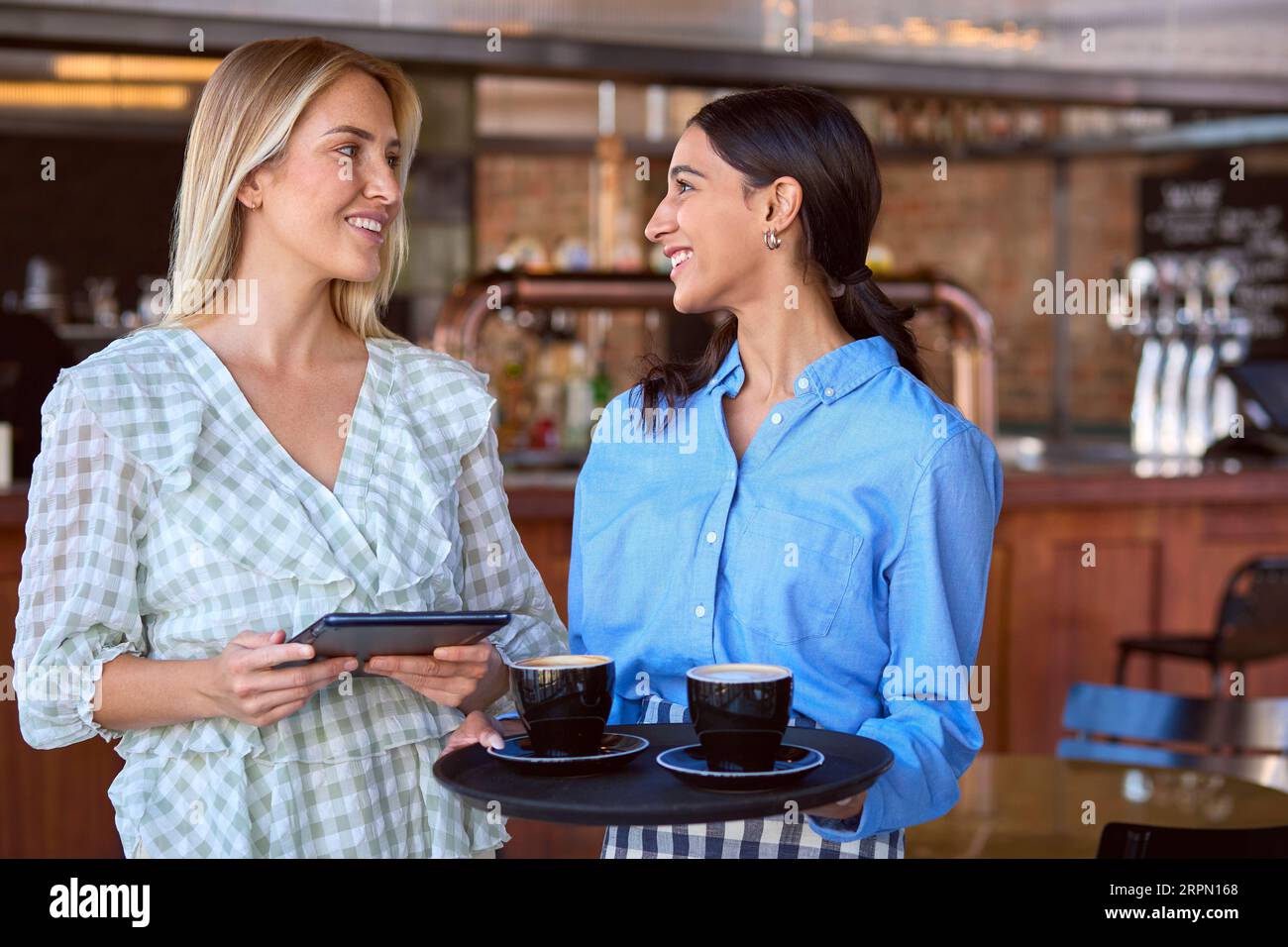 Femme Manager avec tablette numérique et serveuse travaillant dans un restaurant ou un café Banque D'Images