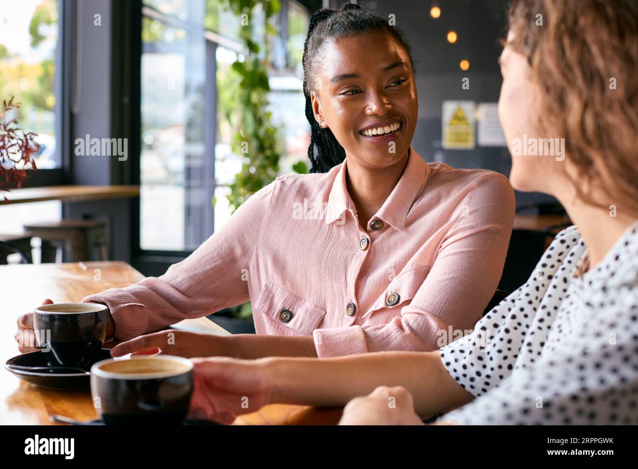 Deux jeunes amies se réunissent dans le café et parlent Banque D'Images
