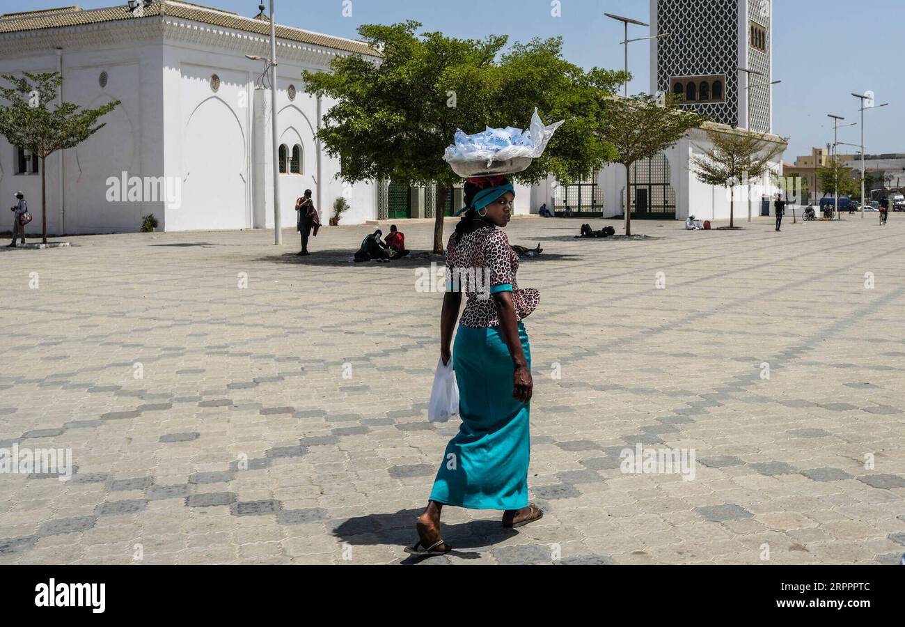 200320 -- DAKAR, le 20 mars 2020 Xinhua -- Une femme vend de l'eau sur une place presque vide à Dakar, au Sénégal, le 20 mars 2020. Le ministre sénégalais de la Santé et de l’action sociale Abdoulaye Sarr a annoncé vendredi soir que neuf nouveaux cas confirmés du nouveau coronavirus COVID-19 ont été détectés au Sénégal. À ce jour, le Sénégal a signalé 47 cas de COVID-19. Cinq patients ont été déclarés guéris par les autorités sanitaires locales. Photo Eddy Peters/Xinhua SÉNÉGAL-DAKAR-COVID-19-CAS PUBLICATIONxNOTxINxCHN Banque D'Images