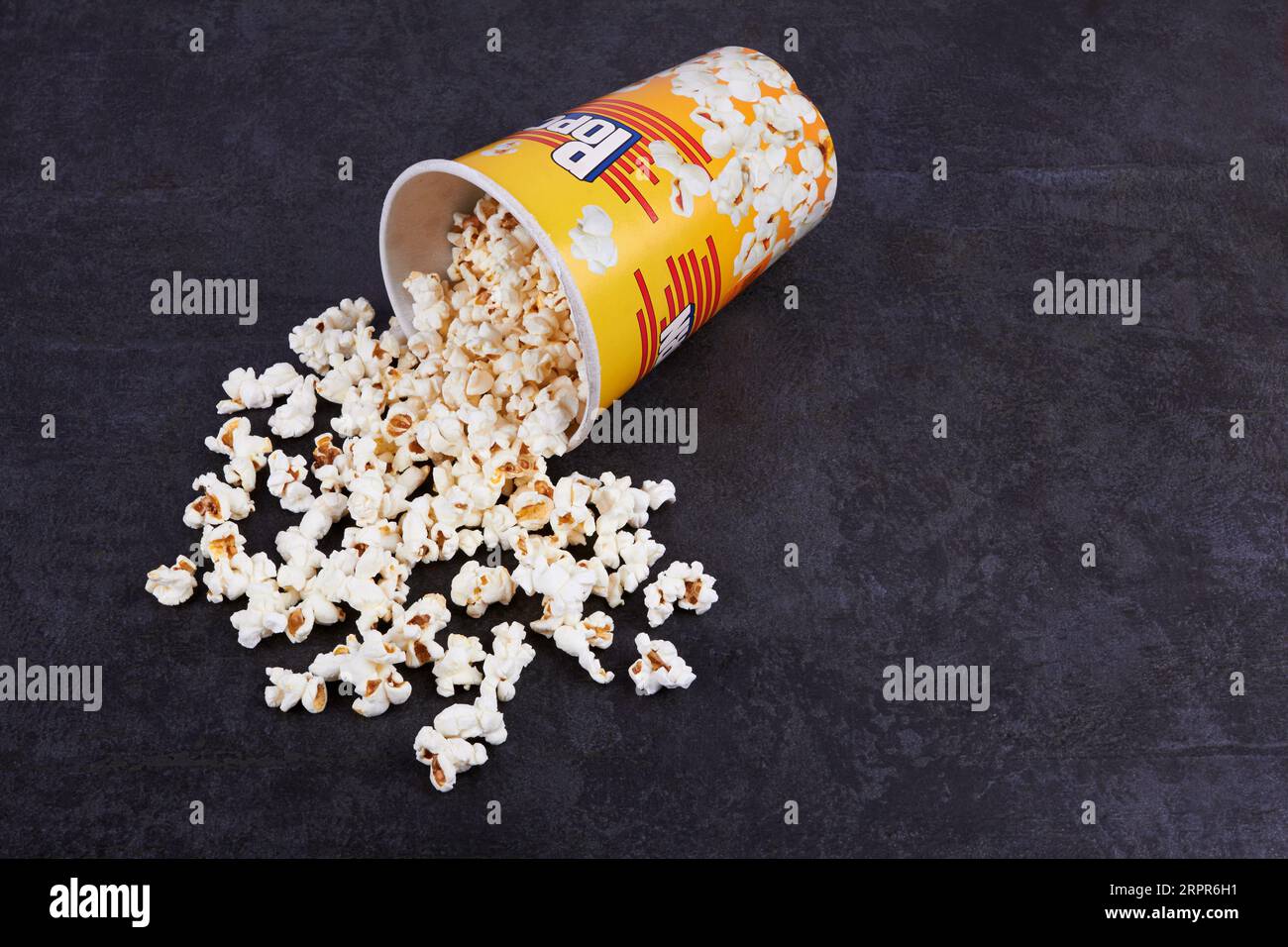 Pop-corn dispersé du seau jaune sur fond sombre Banque D'Images