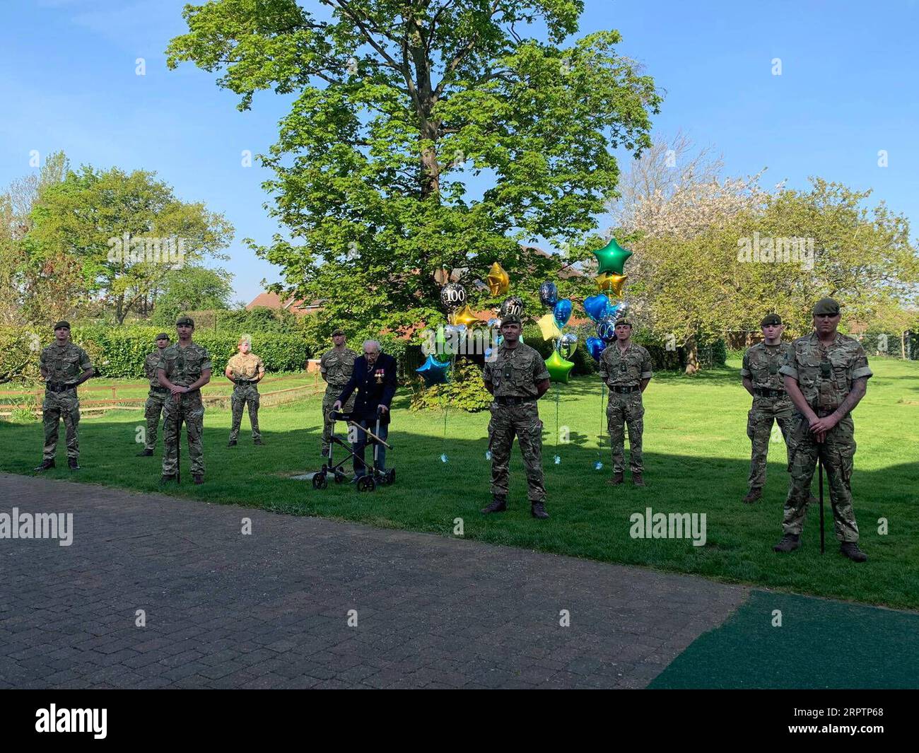 200417 -- LONDRES, le 17 avril 2020 -- Tom Moore, fonctionnaire à la retraite et vétéran de la Seconde Guerre mondiale, se tient avec des membres du 1e Bataillon, The Yorkshire Regiment, après avoir terminé son dernier tour dans son jardin dans le Bedfordshire, en Grande-Bretagne, le 16 avril 2020. Le vétéran de la guerre de 99 ans a recueilli plus de 12 millions de livres et 15 millions de dollars américains pour le National Health Service NHS en accomplissant 100 tours de son jardin. À l'aide d'un cadre de marche, Tom Moore, fonctionnaire à la retraite et vétéran de la Seconde Guerre mondiale, avait prévu de faire 100 tours de son jardin dans le Bedfordshire, en Angleterre, avant son 10 Banque D'Images