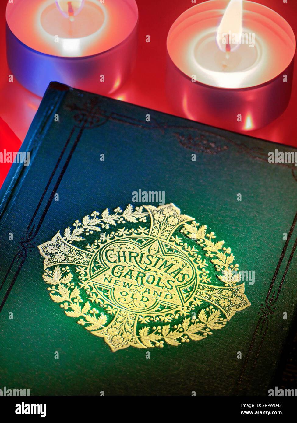 « Christmas Carols » à la chandelle. Couverture de livre de musique ancienne et nouvelle avec des bougies de Noël chaleureuses et accueillantes bougies allumées aux chandelles derrière un événement choral de Noël musical traditionnel. Banque D'Images