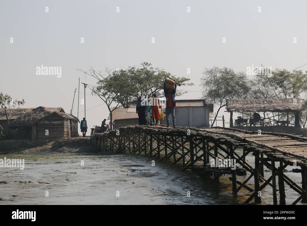 Des villageois marchent sur un pont de bambou pour traverser une rivière au Bangladesh le 5 janvier 2021. Des millions de personnes sont touchées par la crise climatique dans les ceintures côtières du Bangladesh. Banque D'Images