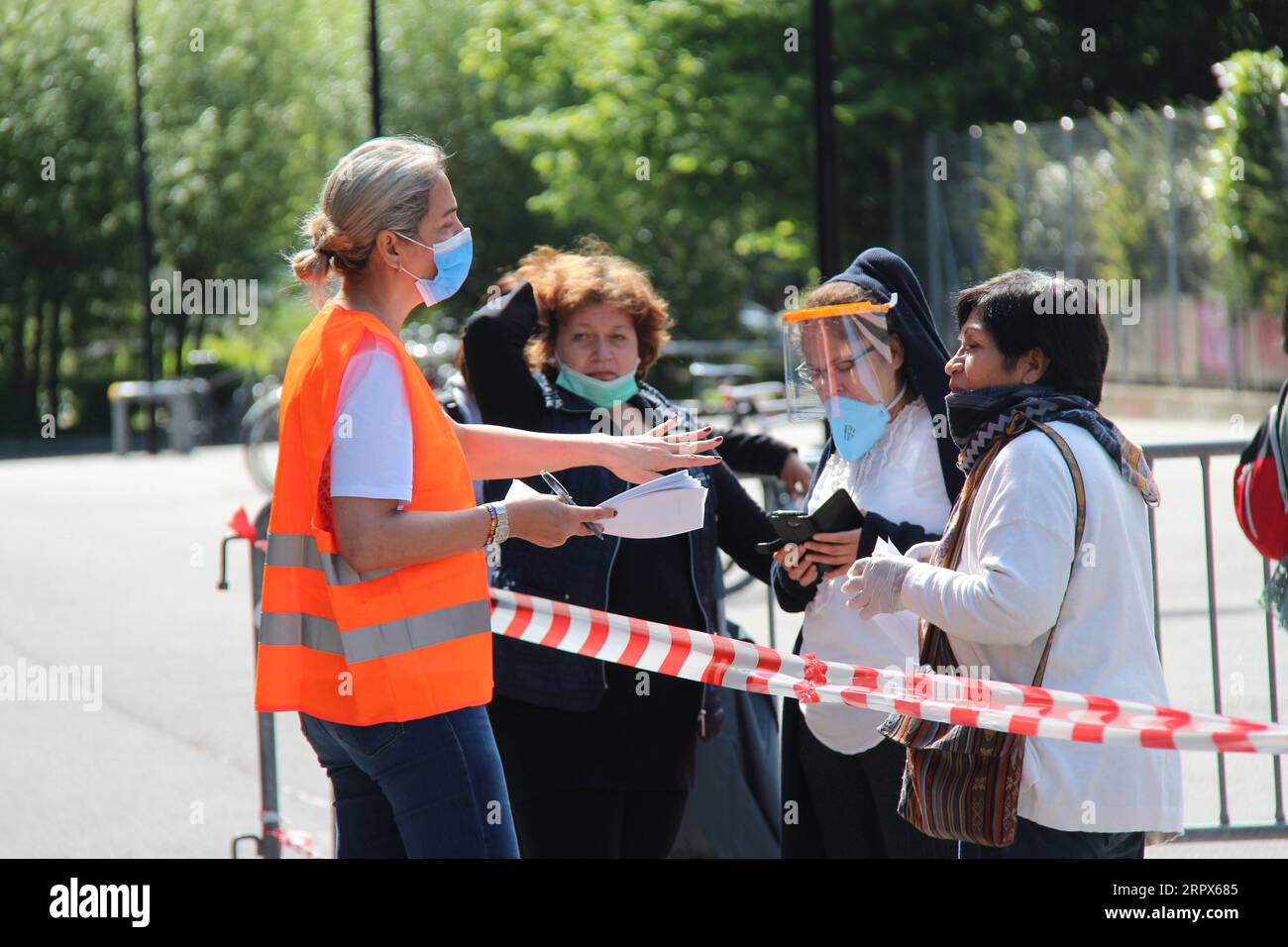 200509 -- GENÈVE, le 9 mai 2020 -- Un volontaire instruit les personnes qui attendent de recevoir des articles de secours dans un stade de Genève, en Suisse, le 9 mai 2020. Afin d’aider les personnes qui ont perdu des revenus pendant l’épidémie et qui n’ont pas pu obtenir une aide à temps, un groupe caritatif distribue des articles de secours dans un stade de Genève tous les samedis. Certains organismes à but non lucratif offrent également des tests COVID-19 gratuits, des consultations juridiques et d’autres services sur place. SUISSE-GENÈVE-COVID-19-RELIEF NiexXiaoyang PUBLICATIONxNOTxINxCHN Banque D'Images