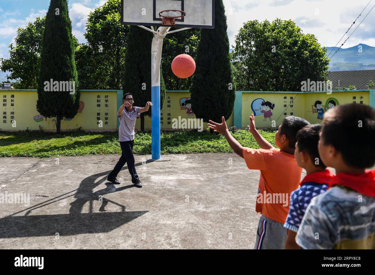 200620 -- WUXUAN, le 20 juin 2020 -- Wei Xuxi joue au basket-ball avec des élèves de l'école primaire de Shuanggui dans la ville d'Ertang, dans le comté de Wuxuan, dans la région autonome de Guangxi Zhuang, dans le sud de la Chine, le 19 juin 2020. Wei Xuxi, un enseignant de 57 ans de la ville d'Ertang dans le comté de Wuxuan, a passé plus de 30 ans à enseigner à la campagne après avoir obtenu son diplôme d'études secondaires en 1985. Il y a 32 élèves en deux classes à l’école primaire de Shuanggui, une petite école où travaille Wei. Au lieu des bâtiments délabrés, ou des tables et des chaises cassées, le multimédia et de nombreux autres équipements d'enseignement de pointe rendent l'école loin f Banque D'Images