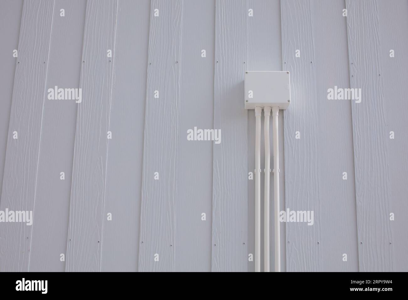 Boîte de jonction électrique en plastique blanc avec conduit installé sur le mur d'une maison en bois blanc Banque D'Images
