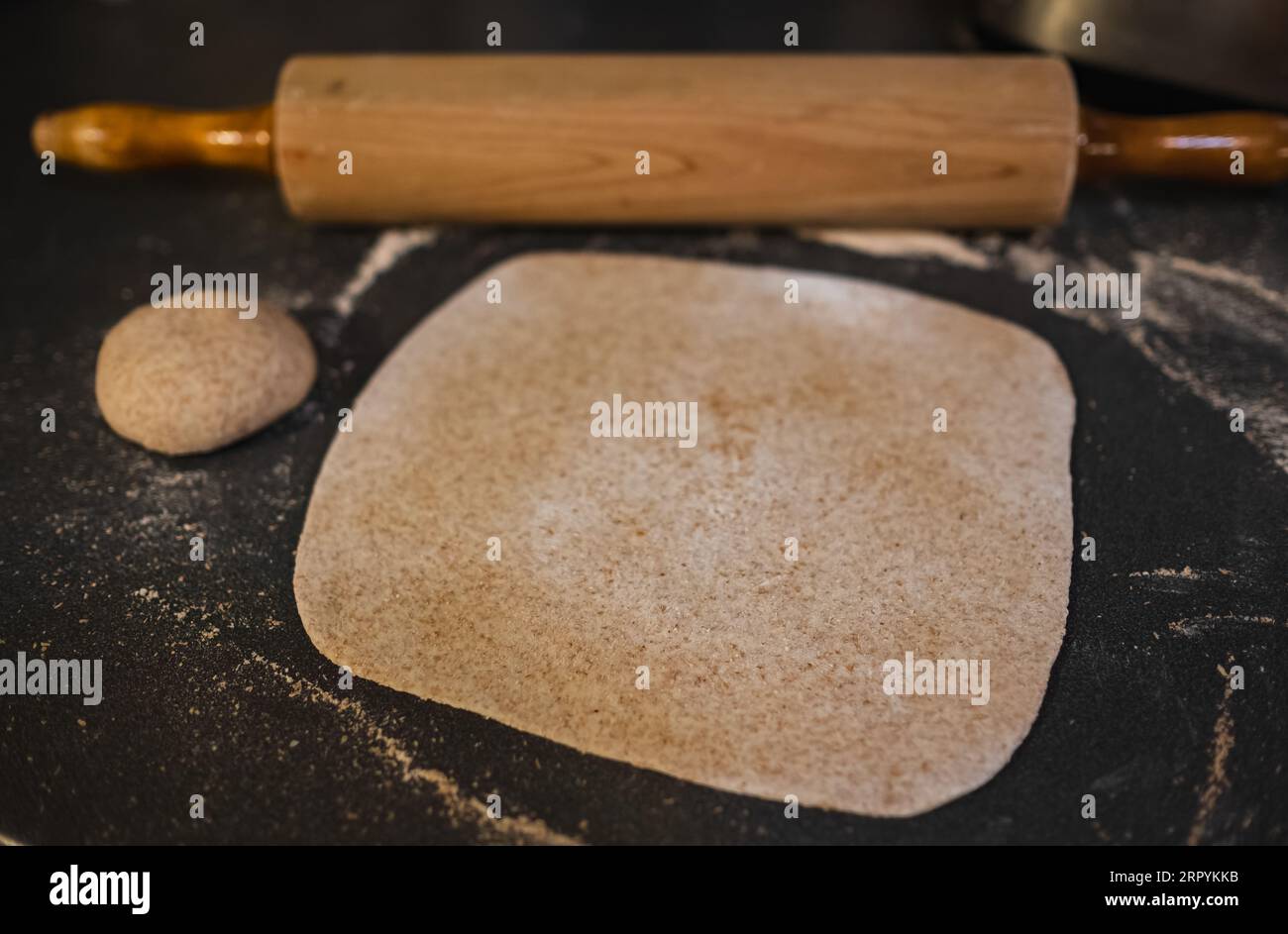 Roulez la pâte complète, le blé, le grain avec le rouleau à pâtisserie vintage sur la table. Pâte bio maison. Pâte roulée sur la table. Banque D'Images