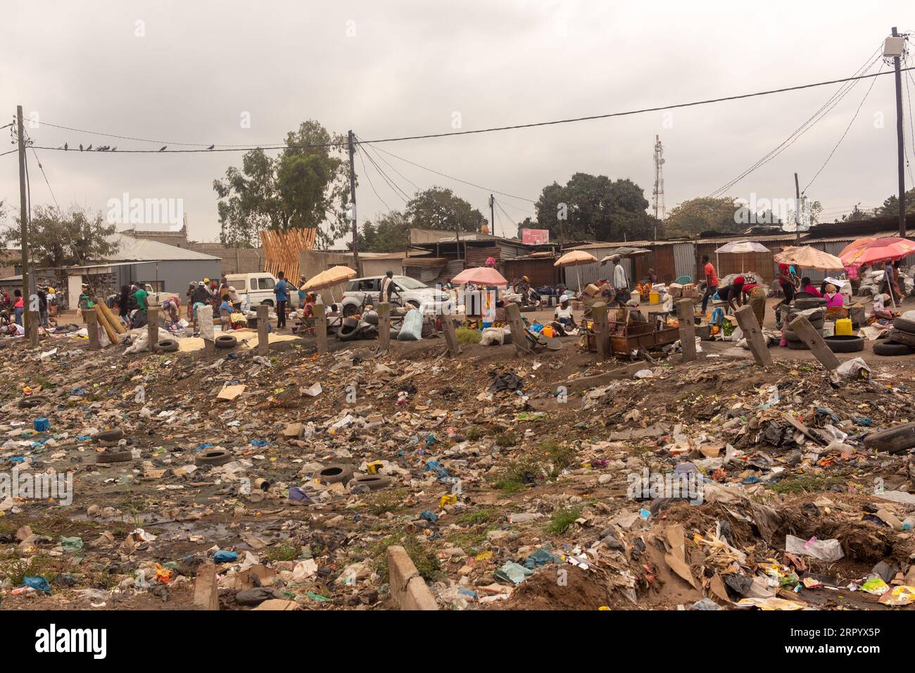 Vallée remplie de déchets près de main Road avec emballages en plastique mis au rebut, eau stagnante et vieux pneus Banque D'Images