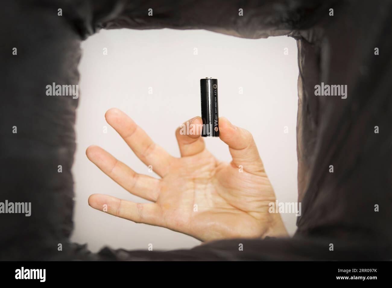 Mise au rebut des batteries. Un homme place les piles AA usagées dans une poubelle. Vue de dessous. Banque D'Images