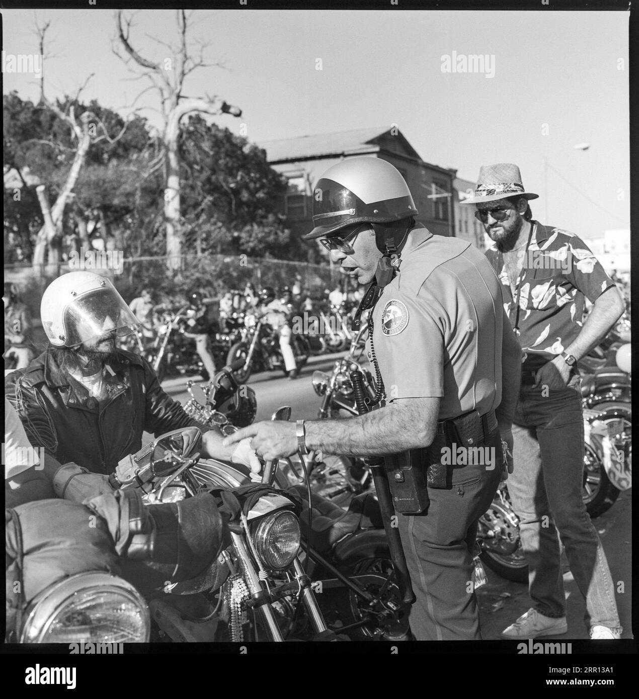 Un policier de moto parle à un motard devant la Boot Hill Saloon pendant la Daytona Bike week en mars 1986 à Daytona Beach, Floride, États-Unis Banque D'Images