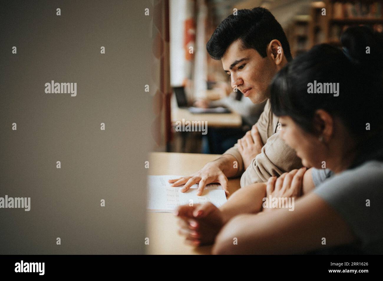 Professeur masculin et étudiant discutant dans la bibliothèque Banque D'Images
