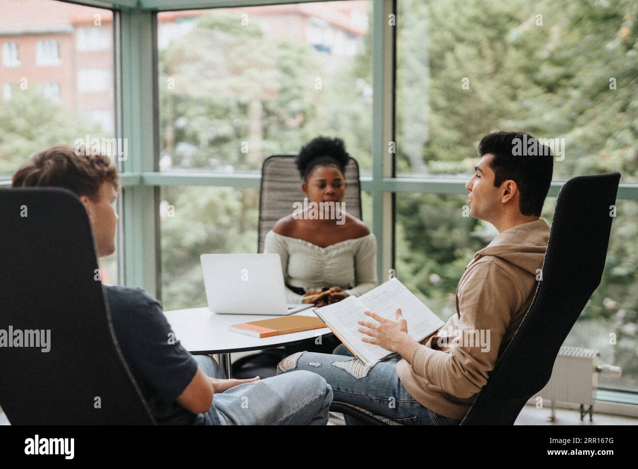 Étudiants multiraciaux discutant tout en étudiant ensemble à l'université Banque D'Images