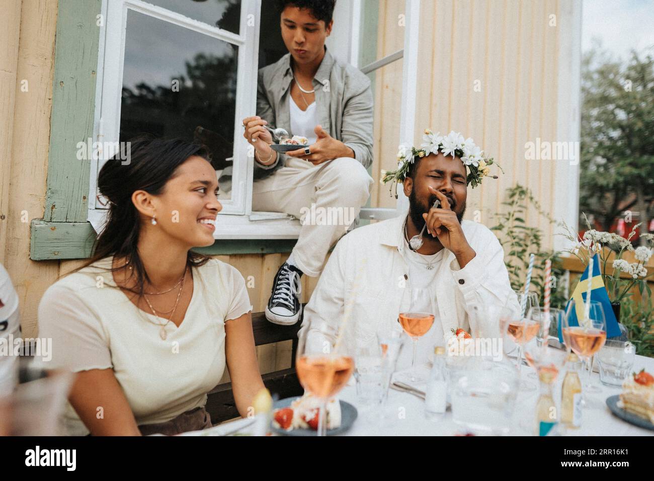 Jeune homme riant en mangeant du gâteau avec des amis pendant le dîner au café Banque D'Images