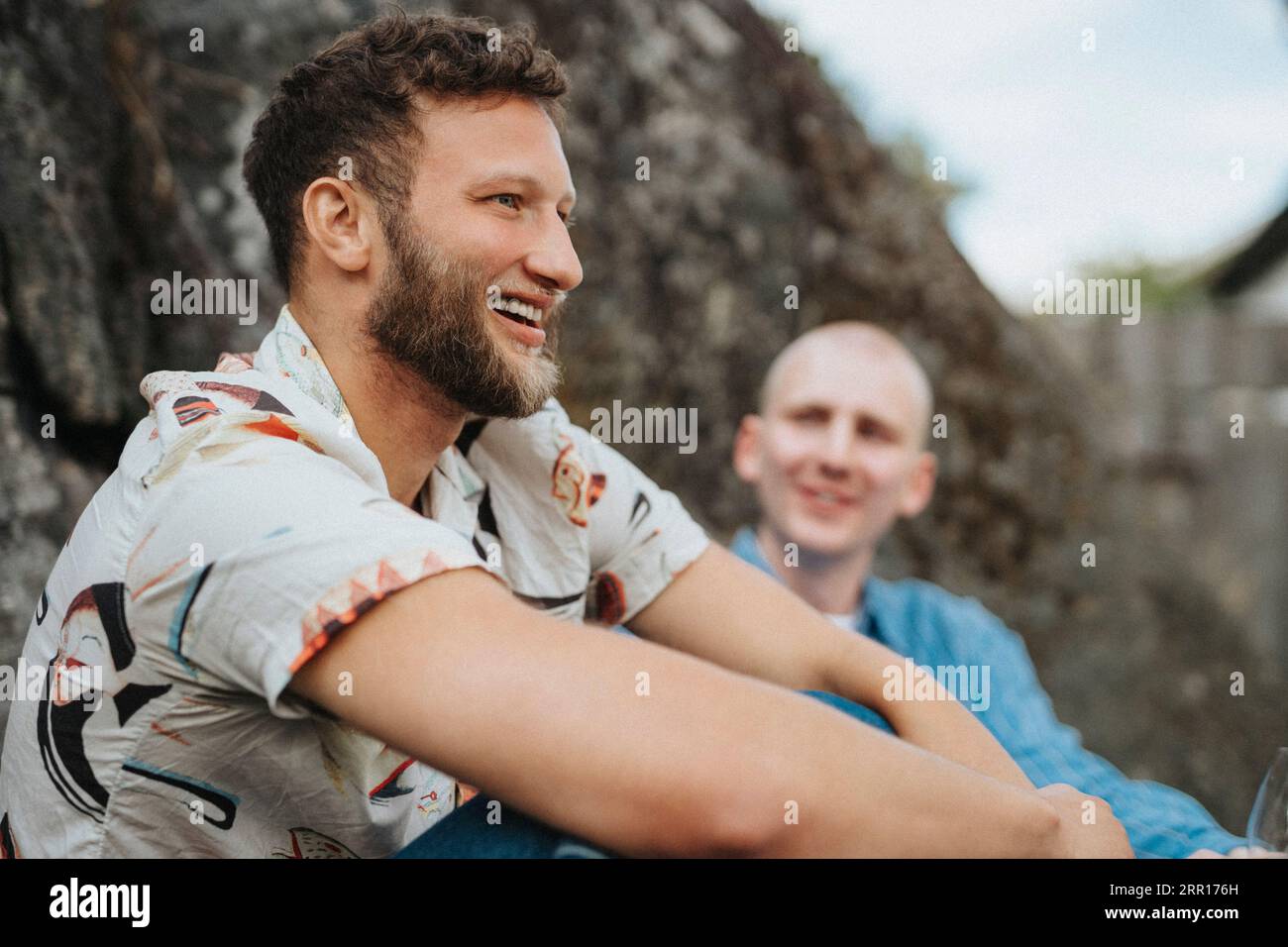 Heureux jeune homme avec la barbe assis avec un ami Banque D'Images