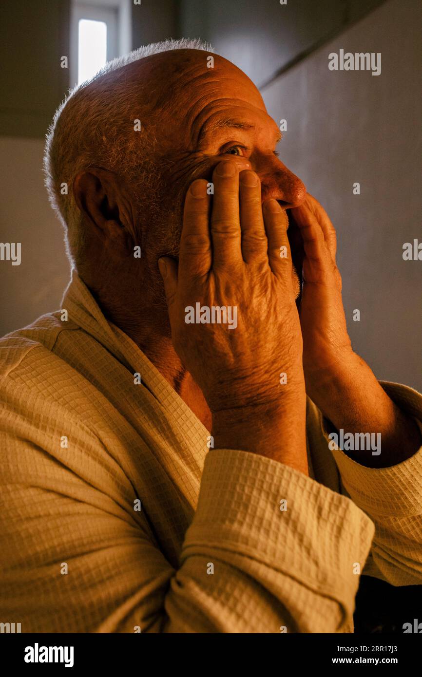 Homme âgé appliquant un hydratant sur le visage dans la salle de bain Banque D'Images