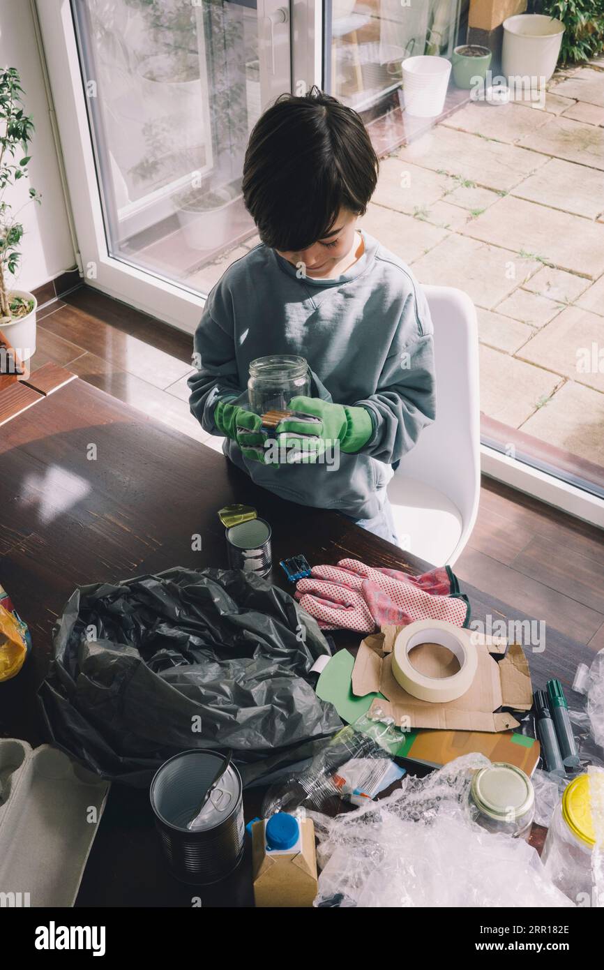 Vue à angle élevé du garçon tenant le récipient en verre à la maison Banque D'Images