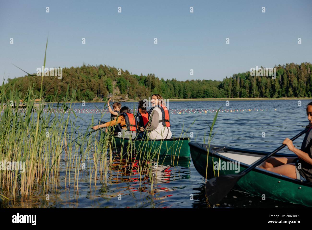 Enfants heureux en profitant tout en faisant du kayak sur le lac au camp d'été Banque D'Images