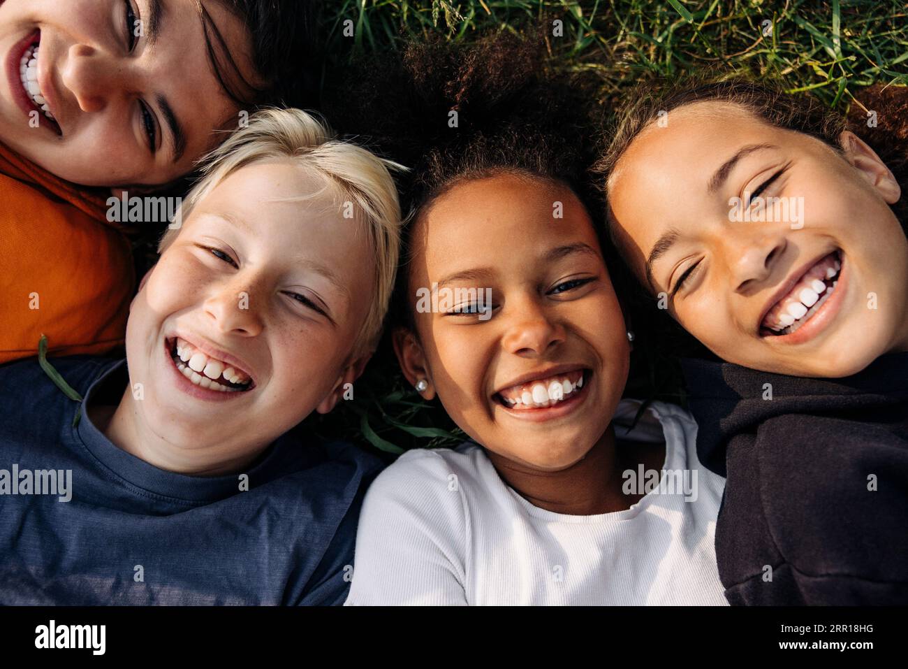 Portrait d'enfants joyeux couchés ensemble sur l'herbe au camp d'été Banque D'Images