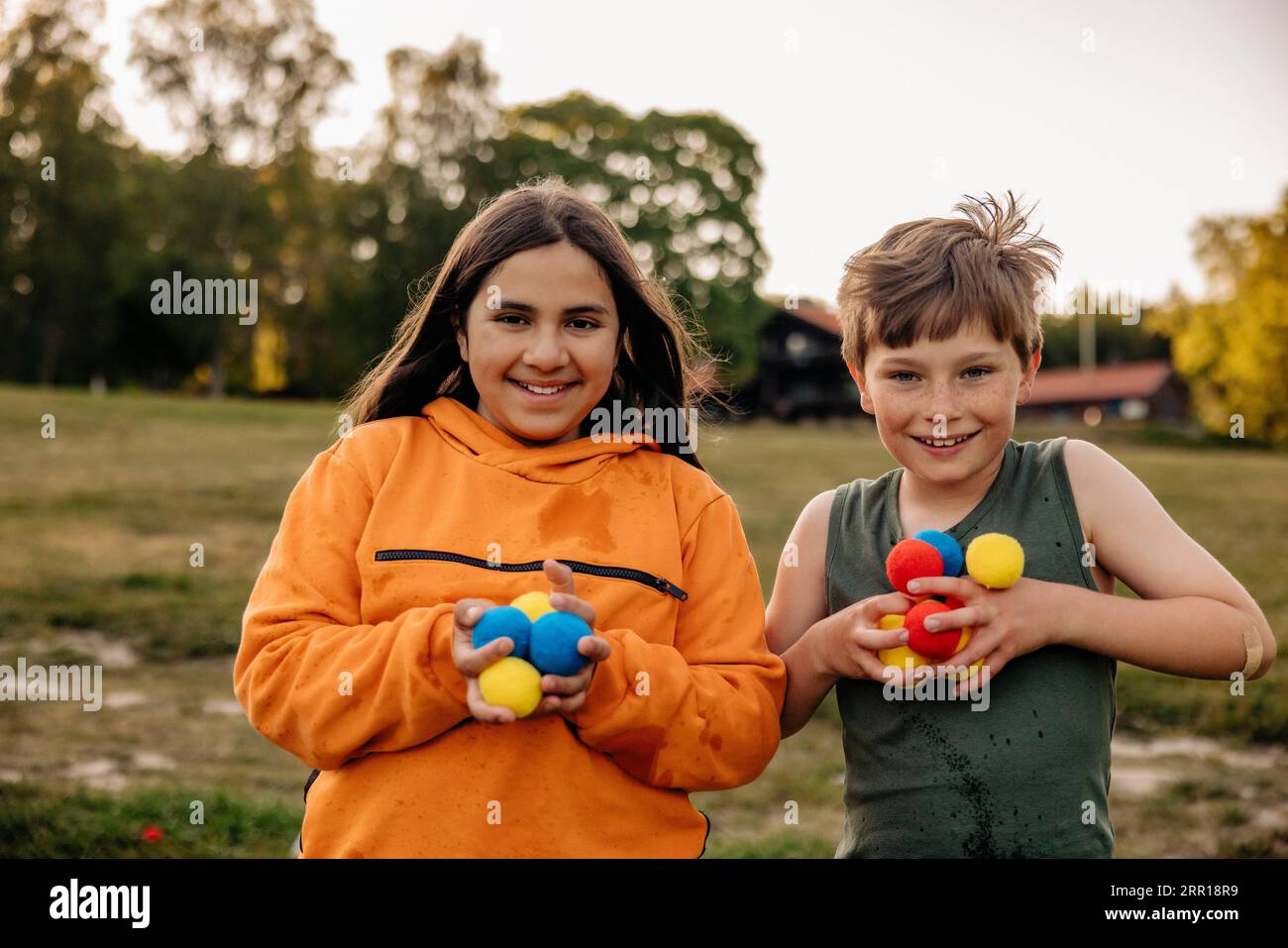 Portrait de heureux amis masculins et féminins tenant des balles multicolores debout dans le terrain de jeu au camp d'été Banque D'Images