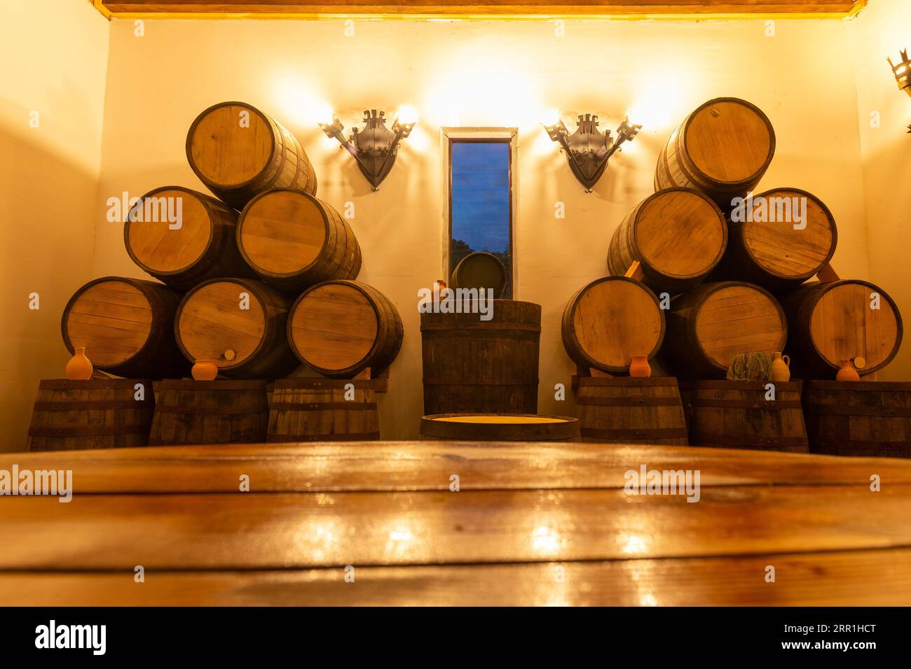 Intérieur du restaurant de vin avec table en bois rustique et fûts de chêne en arrière-plan. Copiez l'espace pour votre produit. Cruches en argile pour boissons. Banque D'Images