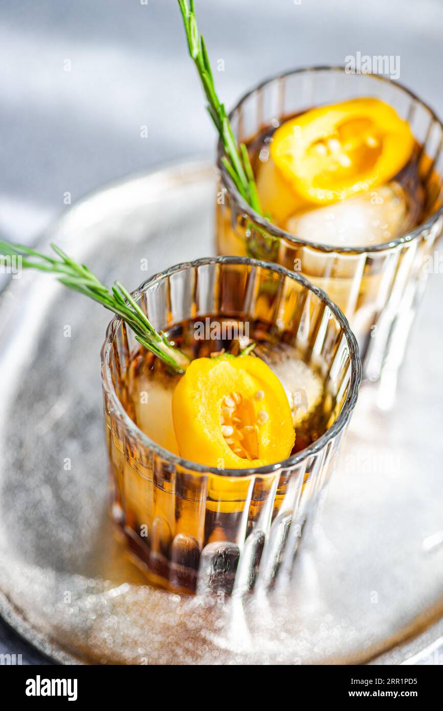 Angle élevé de cocktails Margarita épicés servis avec des glaçons et des tranches de fruits frais placés sur un plateau sur fond gris Banque D'Images