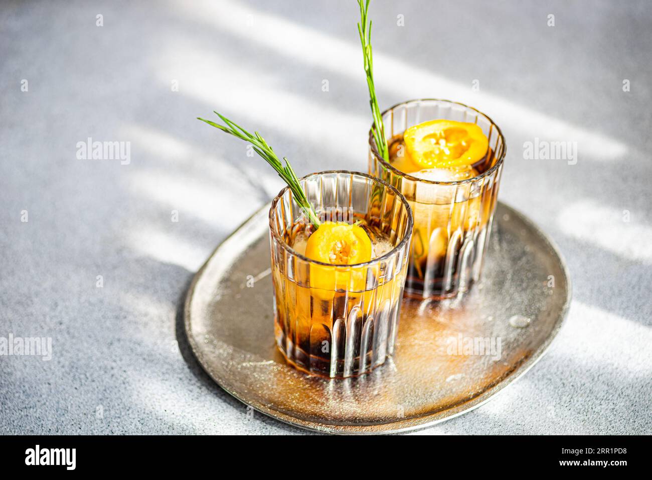 Angle élevé de cocktails Margarita épicés servis avec des glaçons et des tranches de fruits frais placés sur un plateau sur fond gris Banque D'Images