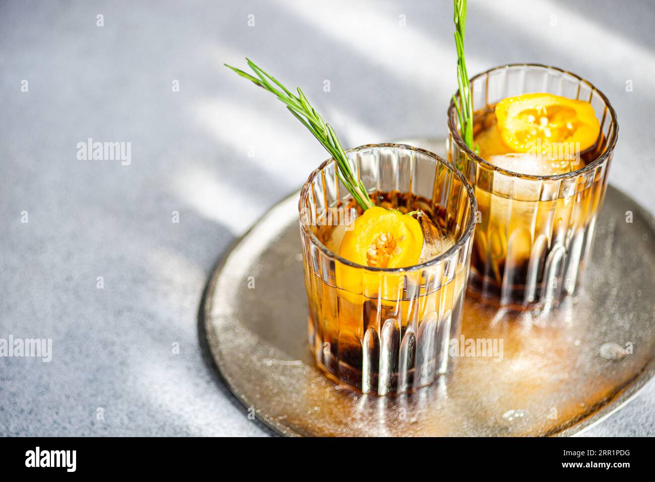 Angle élevé de cocktails Margarita épicés servis avec des glaçons et des tranches de fruits frais placés sur un plateau sur fond gris Banque D'Images