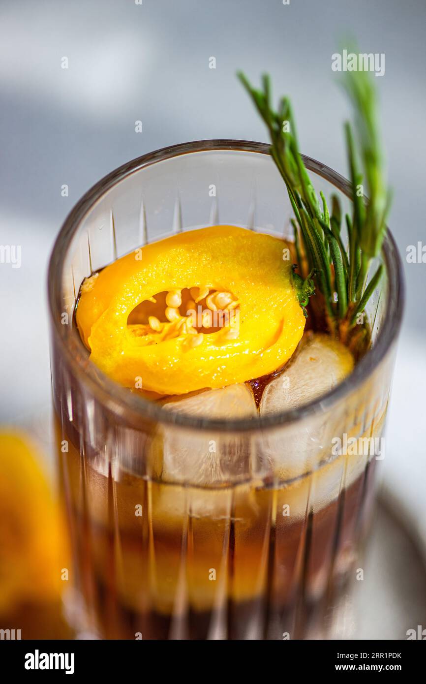 Angle élevé de cocktail Margarita épicé servi avec des glaçons et des tranches de fruits frais placés sur un plateau sur fond gris Banque D'Images