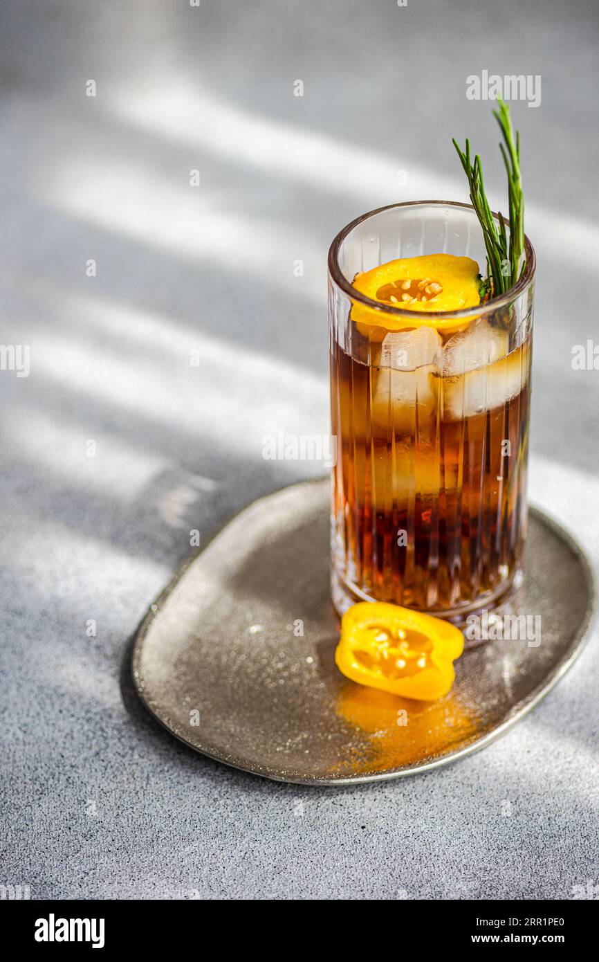 Angle élevé de cocktail Margarita épicé servi avec des glaçons et des tranches de fruits frais placés sur un plateau sur fond gris Banque D'Images