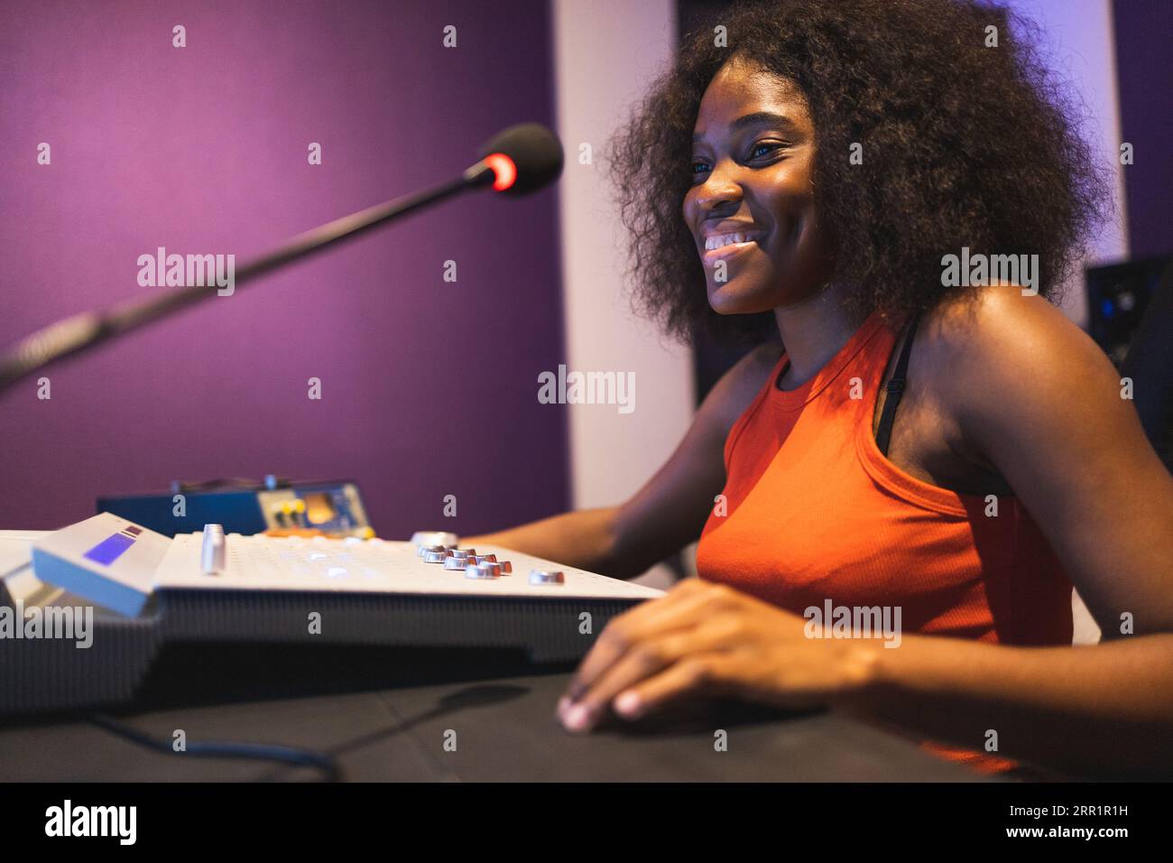 Ingénieure du son afro-américaine joyeuse travaillant dans un studio d'enregistrement de musique et utilisant un tableau de mixage et un logiciel pour créer une chanson moderne Banque D'Images