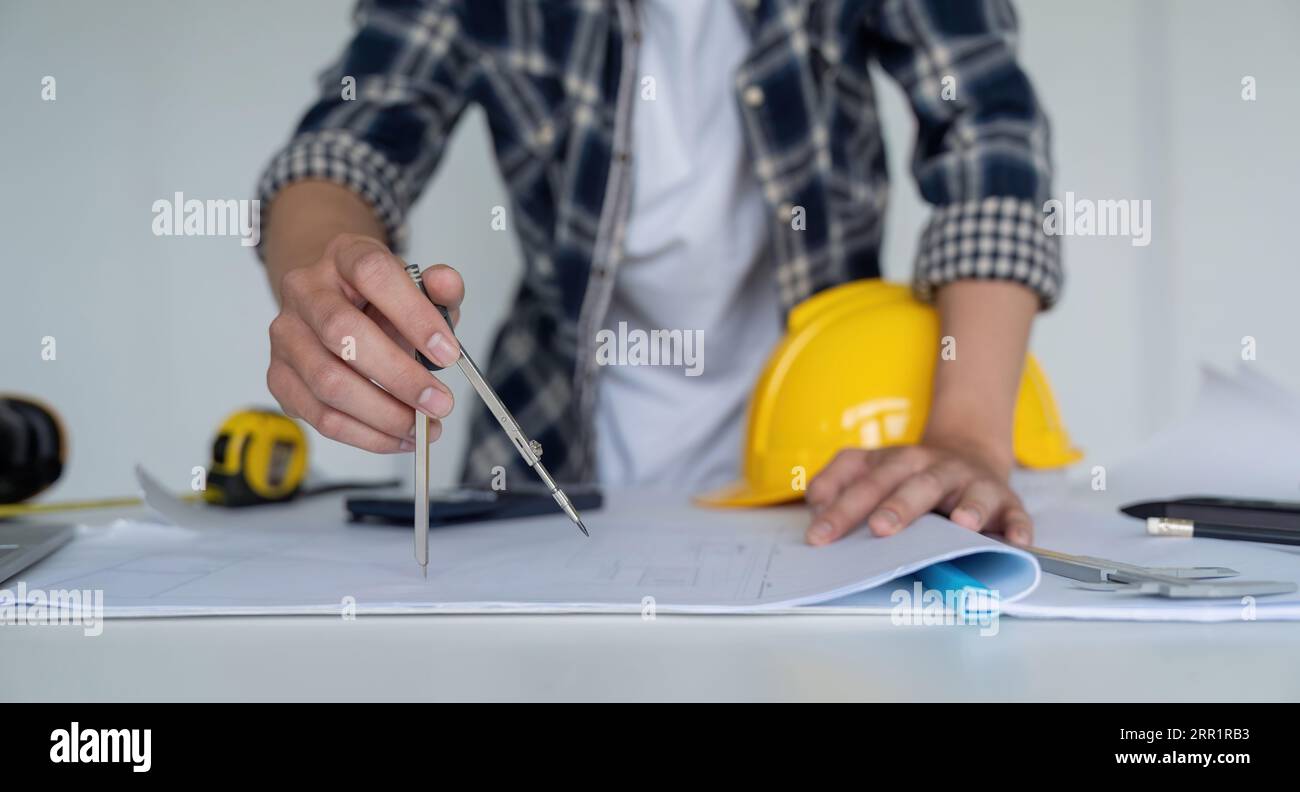 Gros plan de l'ingénieur masculin asiatique travaillant sur le projet architectural de plan au chantier de construction au bureau dans le bureau Banque D'Images