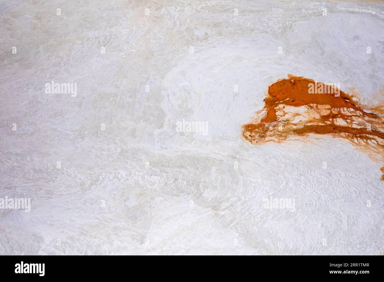 Surface en marbre texturé de pierre blanche avec des lignes chaotiques inégales et une tache orange Banque D'Images