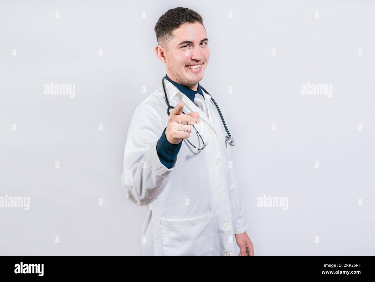 Beau docteur pointant la caméra. Médecin amical et souriant pointant vers vous, jeune médecin pointant vers vous Banque D'Images