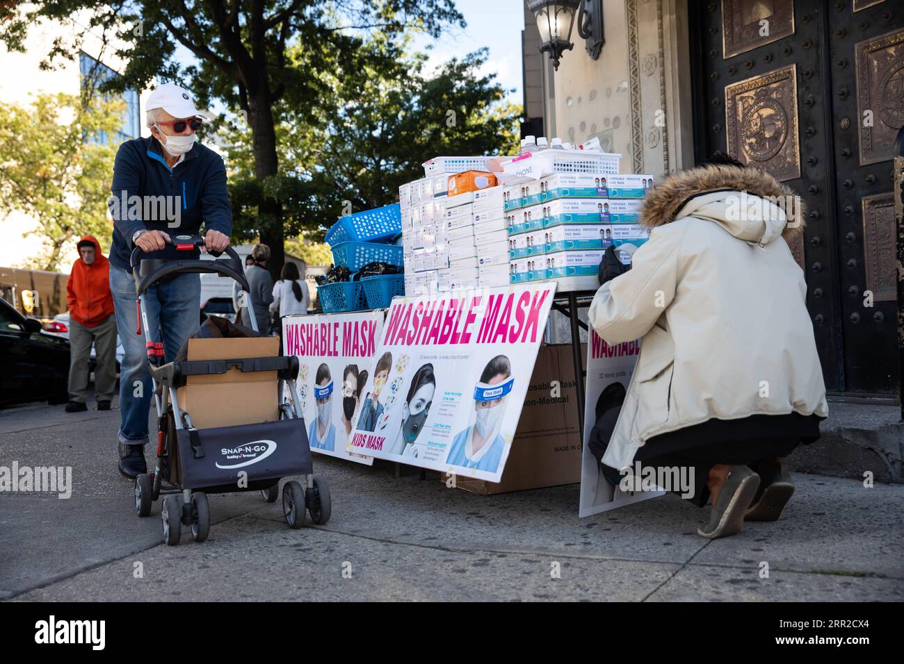 201008 -- NEW YORK, 8 octobre 2020 -- Une personne portant un masque facial pousse une charrette devant un vendeur de rue vendant des équipements de protection individuelle EPI dans le quartier de Midwood, un quartier hotspot COVID-19 à Brooklyn à New York, aux États-Unis, le 8 octobre 2020. Le dernier taux de positivité au coronavirus dans les 20 codes postaux des hotspots dans les comtés de Queens, Brooklyn, Orange et Rockland dans l’État de New York était de 5,8 pour cent, plus de cinq fois le taux de positivité à l’échelle de l’État, à l’exclusion de ces codes postaux, qui s’élevait à 1,01 pour cent, a tweeté jeudi le gouverneur Andrew Cuomo. Fermetures d'entreprises non essentielles, scho Banque D'Images