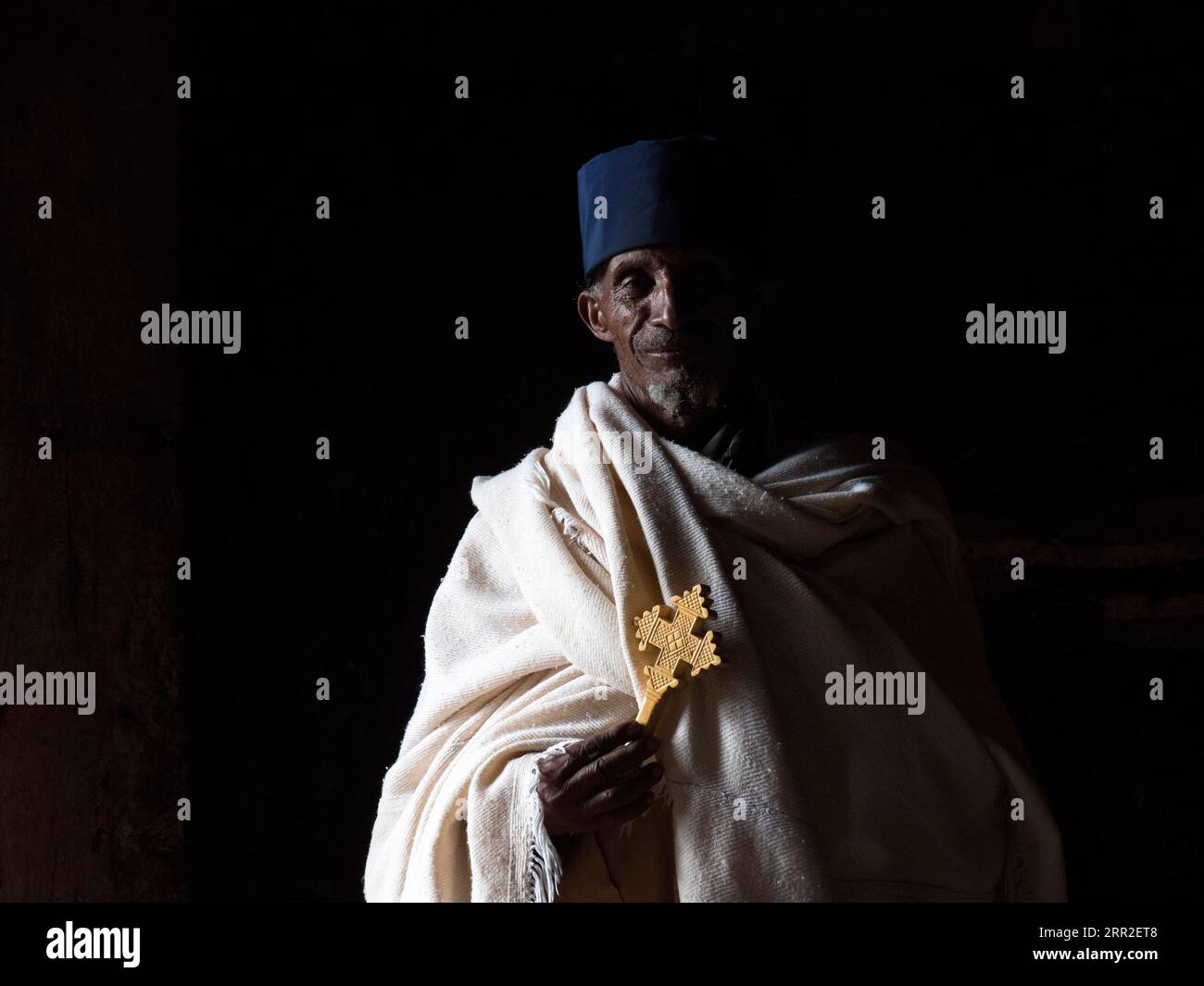 Prêtre avec croix dans la lumière sombre, Gondar, région d'Amhara, Ethiopie Banque D'Images