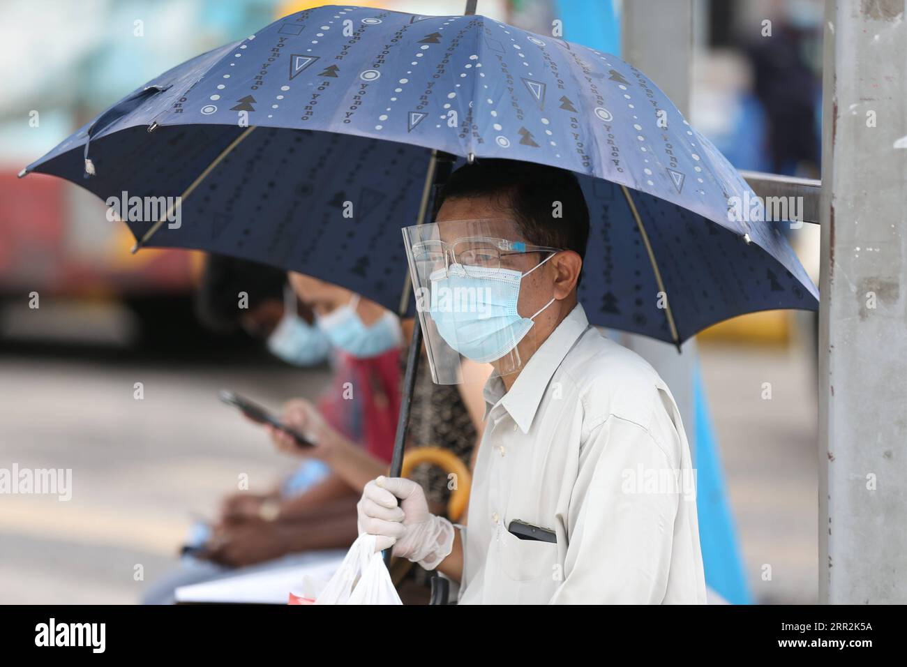 201013 -- YANGON, le 13 octobre 2020 -- Un homme portant un masque et un bouclier facial attend un bus à un arrêt de bus dans le centre-ville de Yangon, Myanmar, le 13 octobre 2020. Le nombre total de cas de COVID-19 au Myanmar est passé à 30 437 mardi, selon un communiqué du ministère de la Santé et des Sports. MYANMAR-YANGON-COVID-19 UxAung PUBLICATIONxNOTxINxCHN Banque D'Images