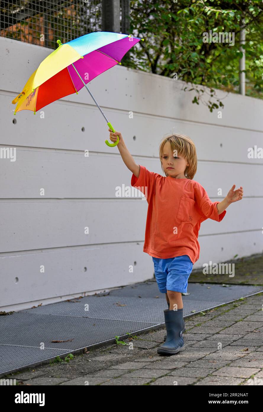 Petit garçon, blond, 5 ans, portant un parapluie coloré, environnement urbain, Stuttgart, Baden-Wuerttemberg, Allemagne Banque D'Images